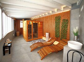 A modern spa with wooden benches, a sauna, and a large white sink.