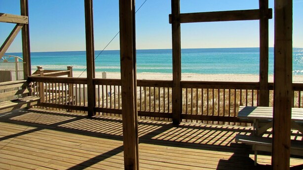 Eine Holzterrasse mit Blick auf Strand und Meer.