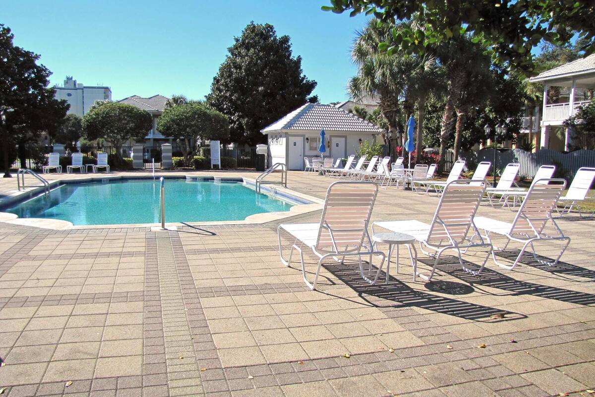 A swimming pool with lounge chairs and a tiled deck.