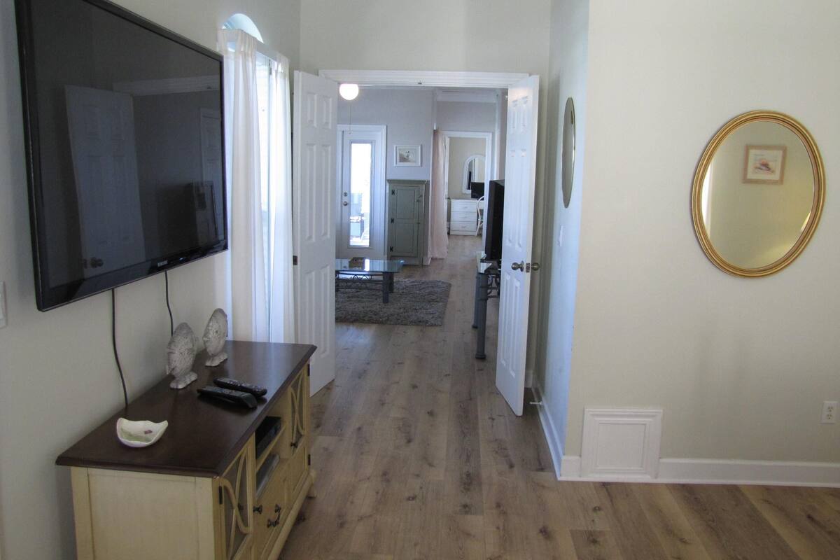 A hallway with a television, a wooden cabinet, and a mirror on the wall.