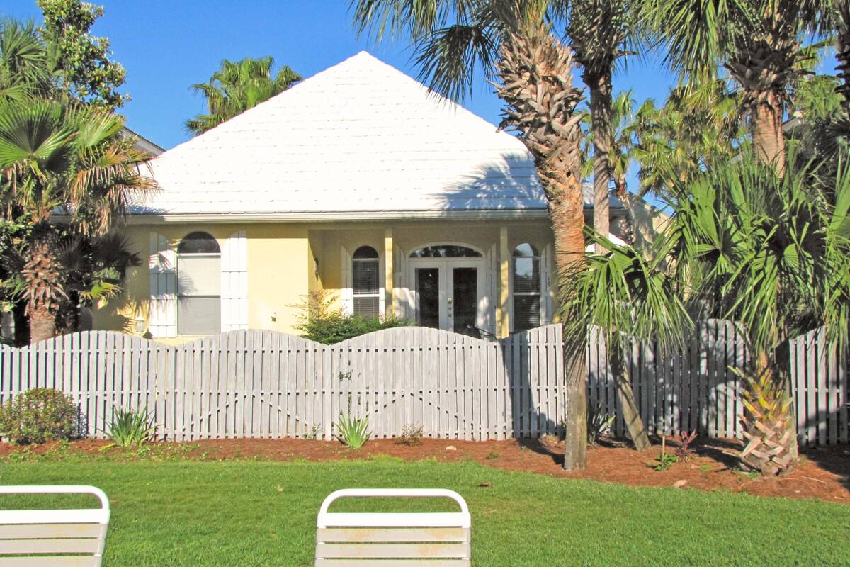 A house with a white roof, a wooden fence, and a lawn.