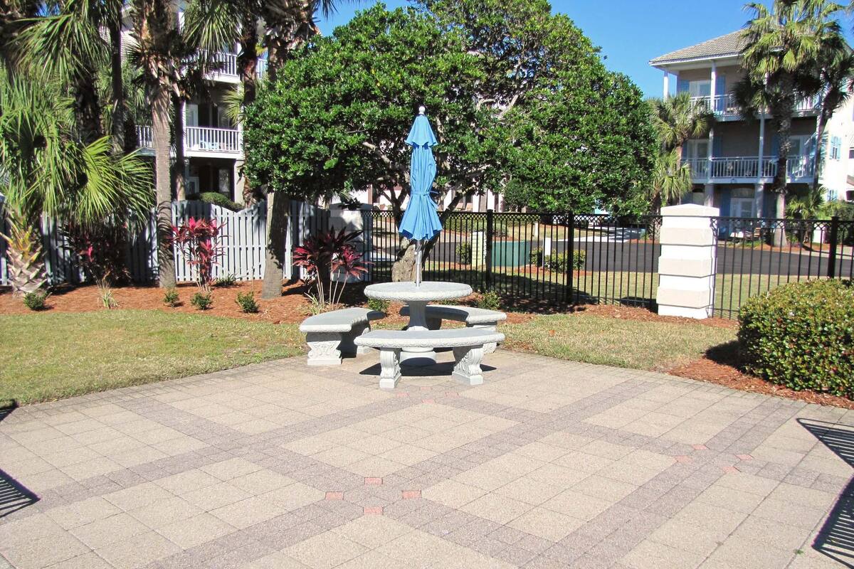 A courtyard with a fountain, seating, and a blue umbrella.