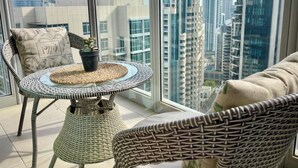A balcony with wicker furniture, a small table, and a potted plant. - Maison Privee - Exclusive Apt w/ Burj Khalifa Next Door (Dubai)