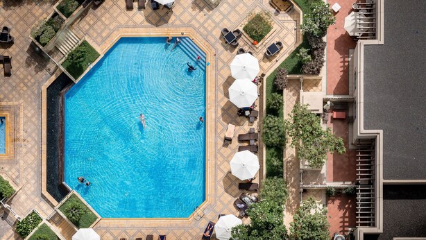 An aerial view of a swimming pool surrounded by outdoor seating and greenery. - Maison Privee - Exclusive Apt w/ Burj Khalifa Next Door (Dubai)
