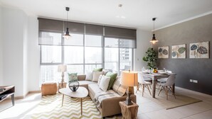 A modern living room with a sofa, coffee table, and dining area. - Maison Privee - Exclusive Apt w/ Burj Khalifa Next Door (Dubai)
