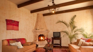 A living room with a fireplace, two sofas, a coffee table, and a television.