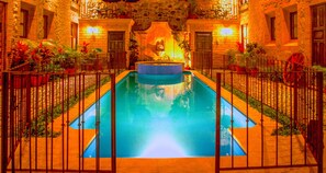 A swimming pool with a central fountain, surrounded by a stone wall and potted plants. - Casa San Juan (Antigua Guatemala)