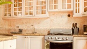 A kitchen with white cabinets, a stove, and a tiled floor.