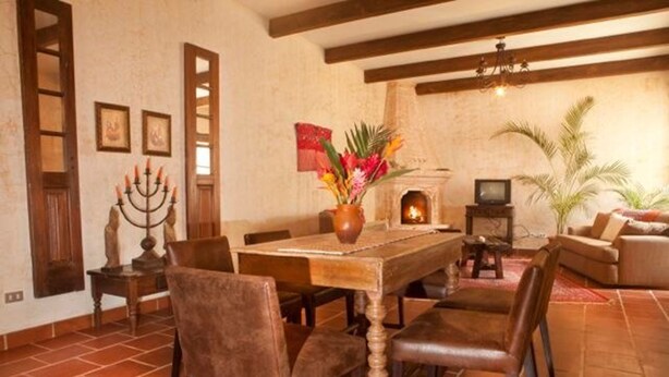 A traditional dining room with a wooden table, chairs, a candelabrum, and a fireplace.
