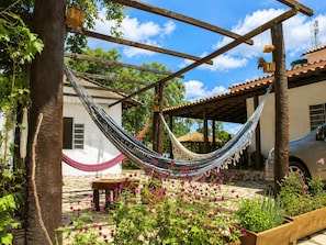 A hammock between wooden beams, a stone patio, and a vehicle. -  Paz e Tranquilidade - Casa para 20 pessoas com 7 quarto (Capitólio)