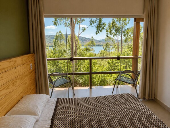 Un dormitorio con una ventana grande, una cama y dos sillas.