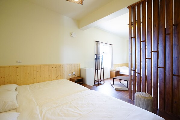 Un dormitorio con una cama grande, cabecera de madera, una mesita de noche, un taburete pequeño y una partición de madera.