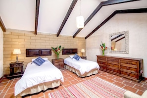 Una habitación con dos camas, un aparador de madera, un espejo y una pared de ladrillo.