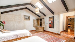 A bedroom with a large bed, a wooden cabinet, a red and white patterned rug, and a skylight. - Casa Santa Catarina (Antigua Guatemala)