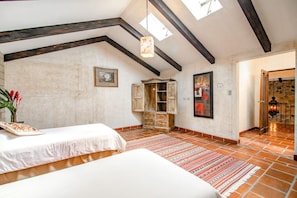 Un dormitorio con una cama grande, un armario de madera, un tapete con estampado rojo y blanco y un tragaluz.