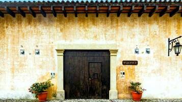 Une façade d'immeuble avec une grande porte en bois, des plantes en pot et une enseigne sur laquelle on peut lire « QUINCE ».