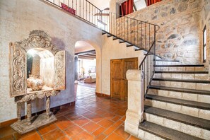 Un pasillo espacioso con una escalera de piedra y un espejo decorativo.