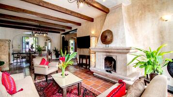 A spacious living room with a fireplace, comfortable seating, and a television mounted on the wall.