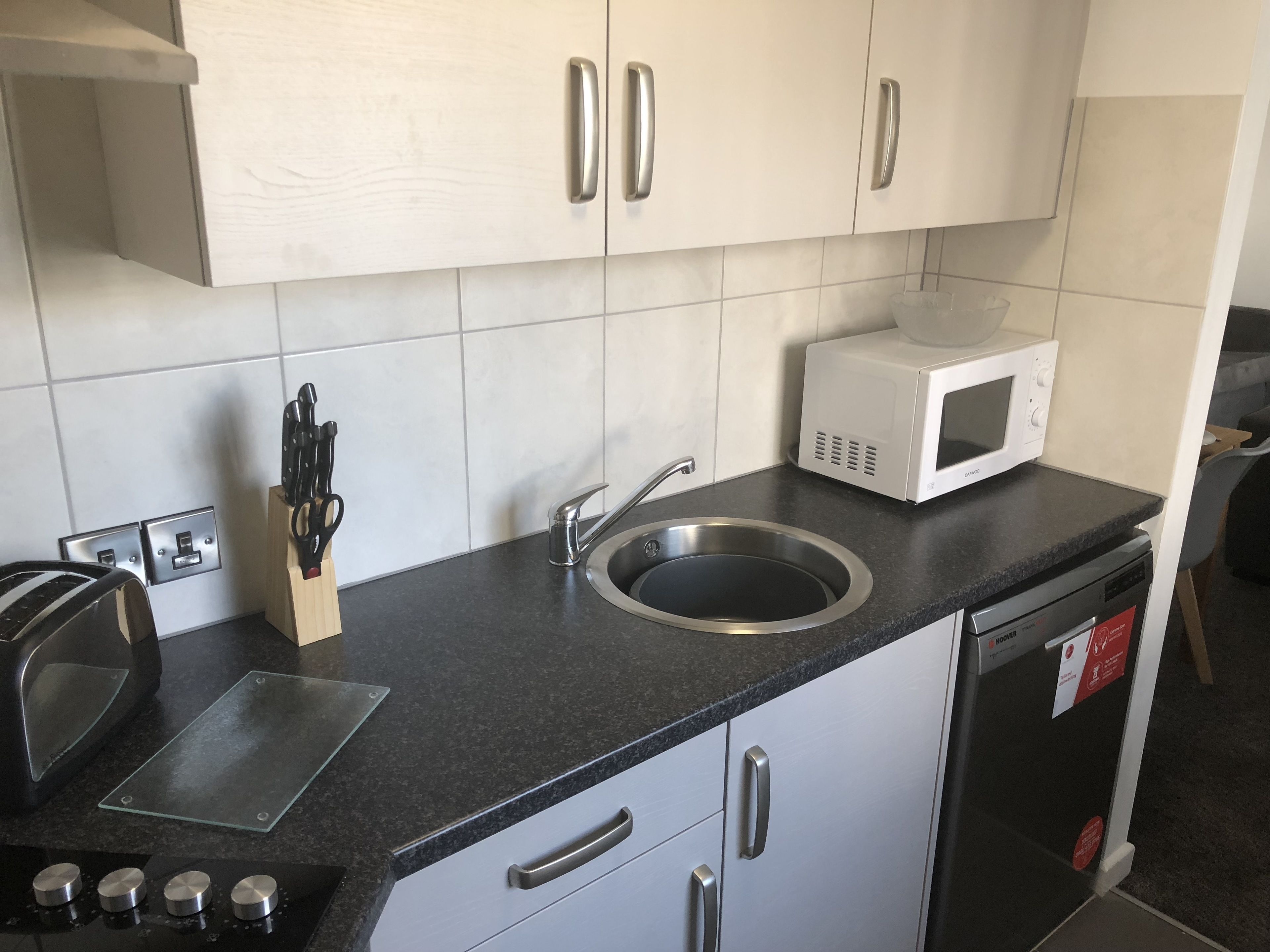 A modern kitchen with a stainless steel sink, a microwave, and a toaster.