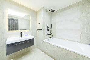 A modern bathroom with a large bathtub, a vanity with a mirror, and a shower area. - Maison Privee - Beach Access Apt w/ Burj & Sea Views on The Palm (Dubai)