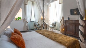 Un dormitorio con una cama grande, dos sillas, una mesita y un armario.