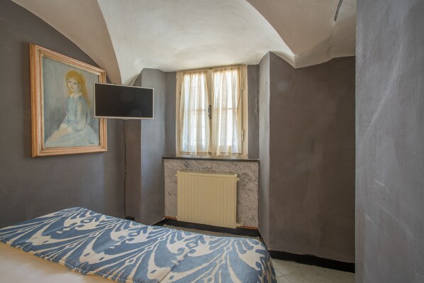A bedroom with a bed, a painting, a window with curtains, and a radiator. - Villa Shelley Boutique Hotel (Lerici)