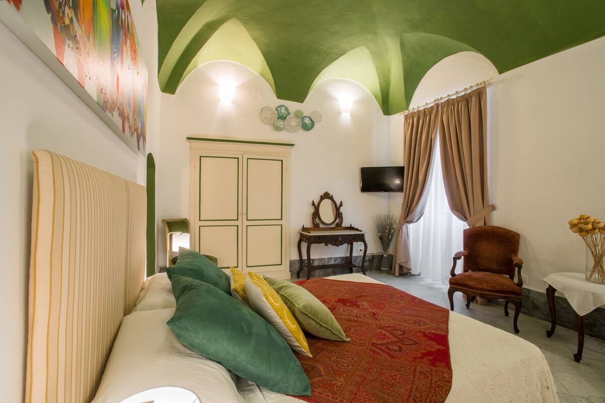 Un dormitorio con una cama, una silla, un televisor y un escritorio.