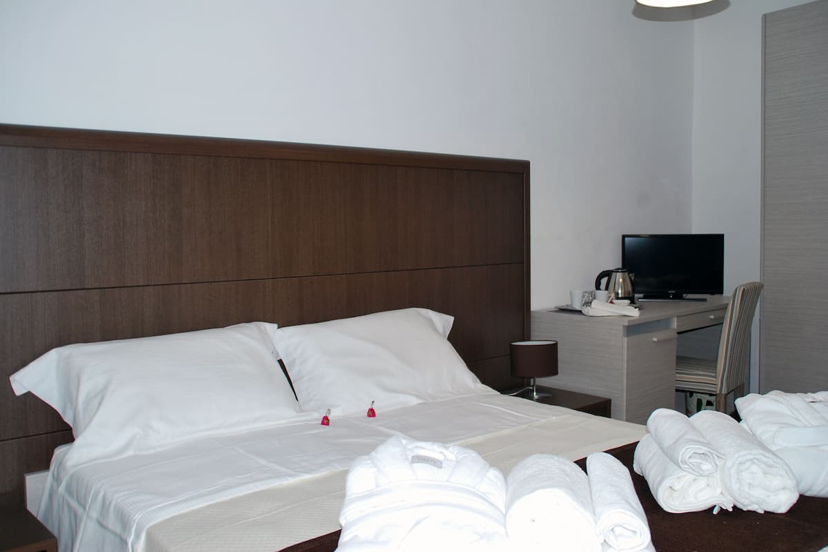 Une chambre d’hôtel avec un lit, un bureau avec une télévision et une chaise.