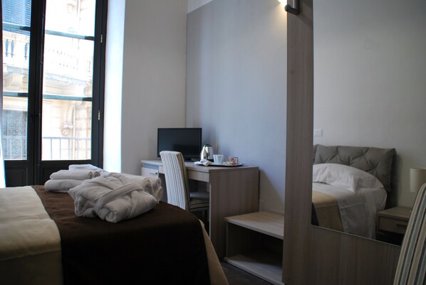 Een hotelkamer met een bed, een bureau met een computer en een spiegel.