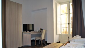 Een hotelkamer met een bed, een bureau met stoel, een televisietoestel en een raam met gordijnen.