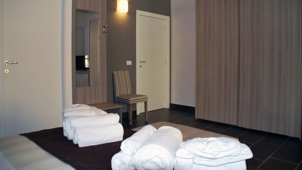 Een hotelkamer met een bed, een stoel en een stapel handdoeken.