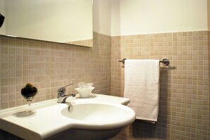 Une salle de bain avec un lavabo, un verre de vin et un porte-serviettes.