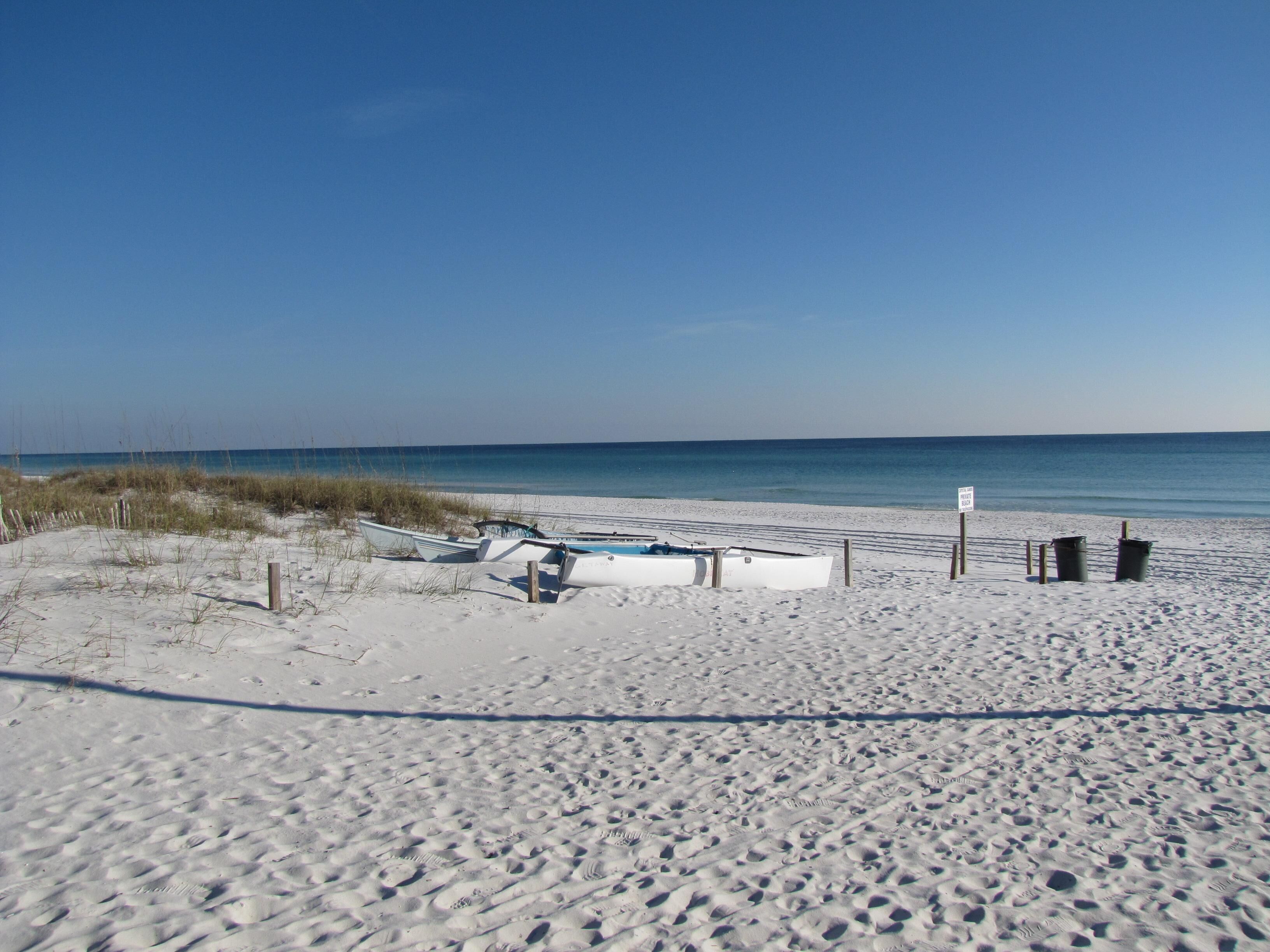 A sandy beach with several boats and a sign indicating a no swimming zone.