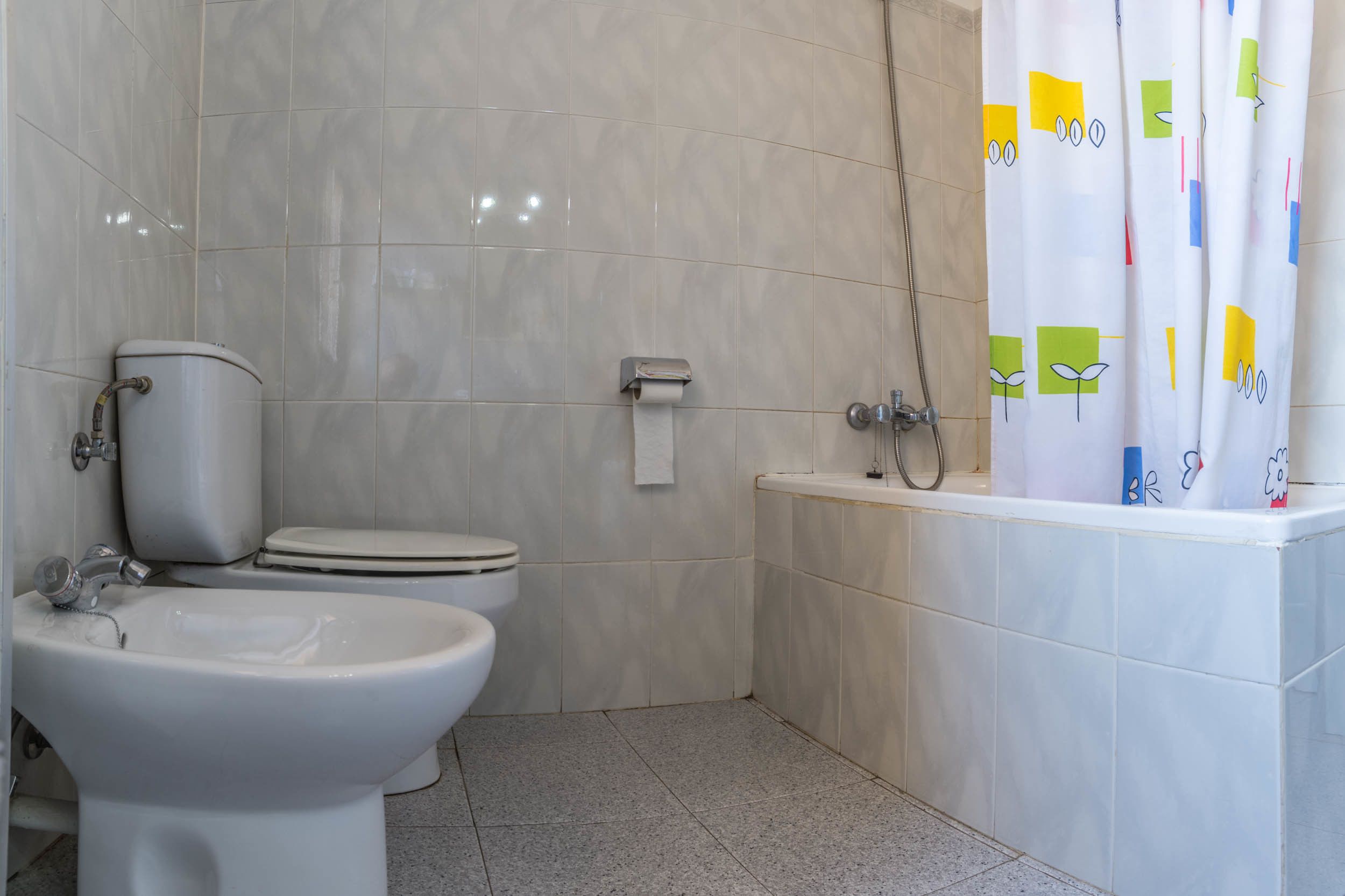 A bathroom with a toilet, bidet, and bathtub.