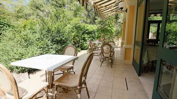 An outdoor patio with a covered seating area, surrounded by lush greenery.