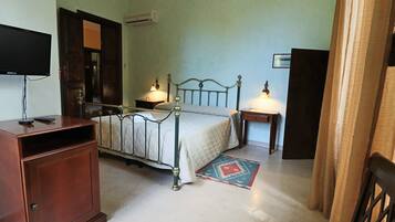 Ein Schlafzimmer mit einem Bett, Nachttischen mit Lampen, einem Fernseher, einem Kleiderschrank und einem Teppich.