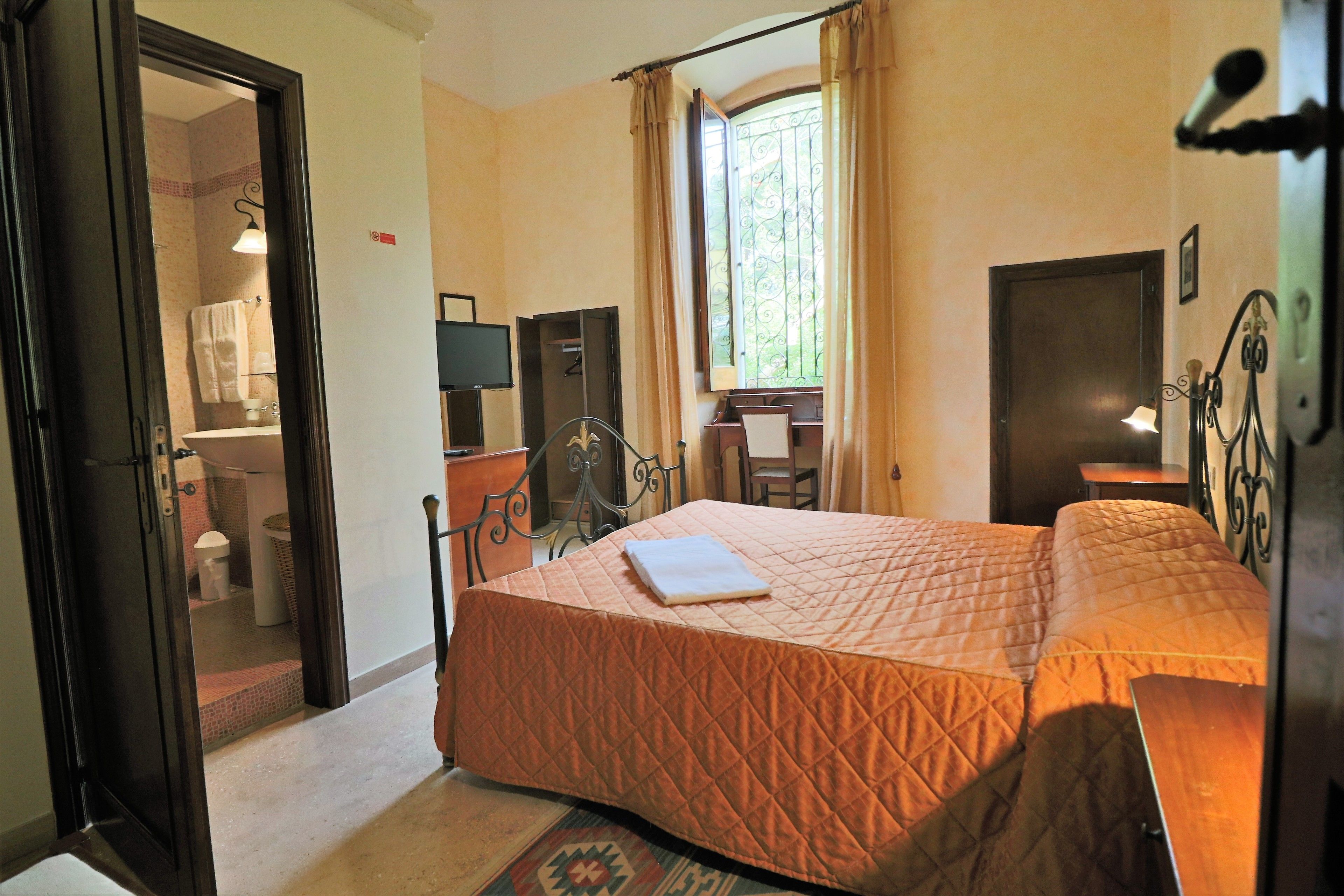 Une chambre à coucher avec un lit, un bureau et une fenêtre avec des rideaux.