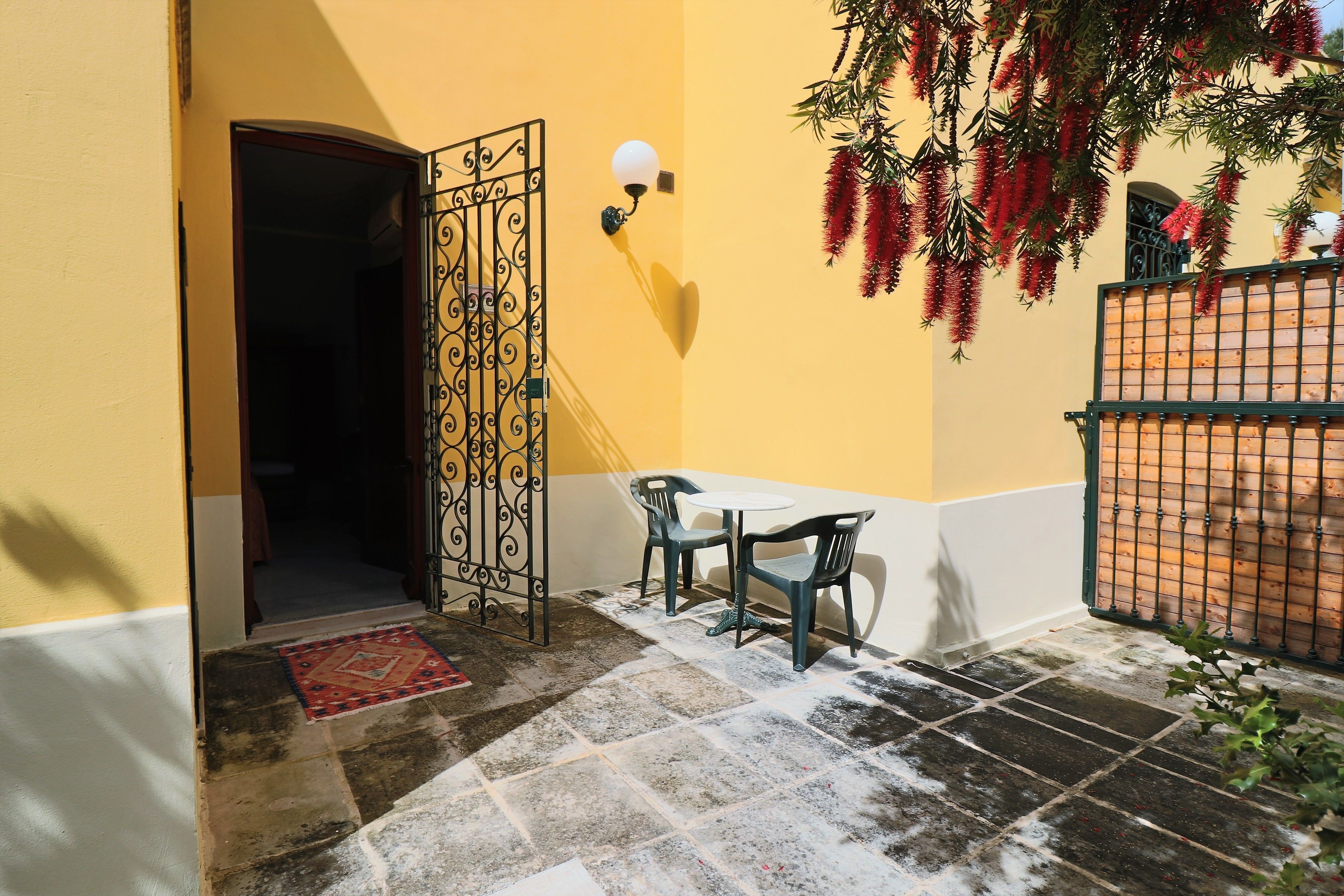 A courtyard with a table and chairs, a decorative gate, and a wall with hanging plants.