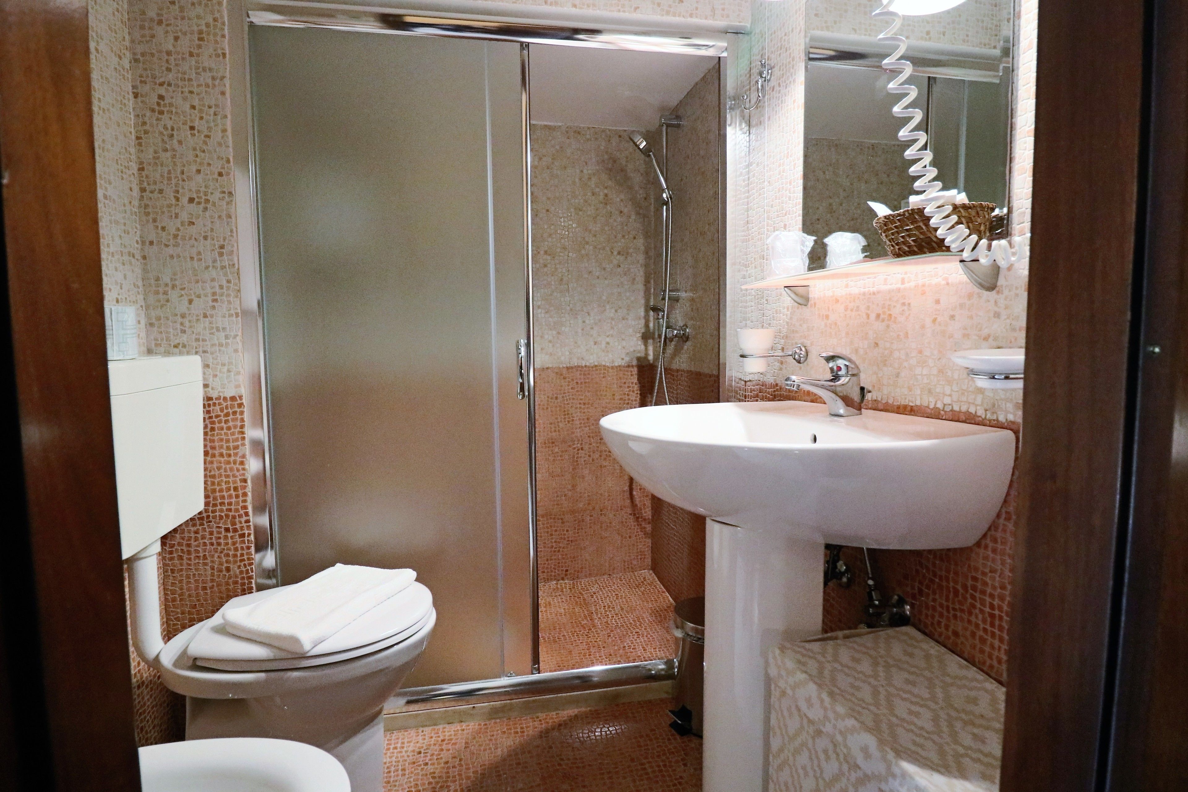 A bathroom with a glass-enclosed shower, a white sink, and a toilet.