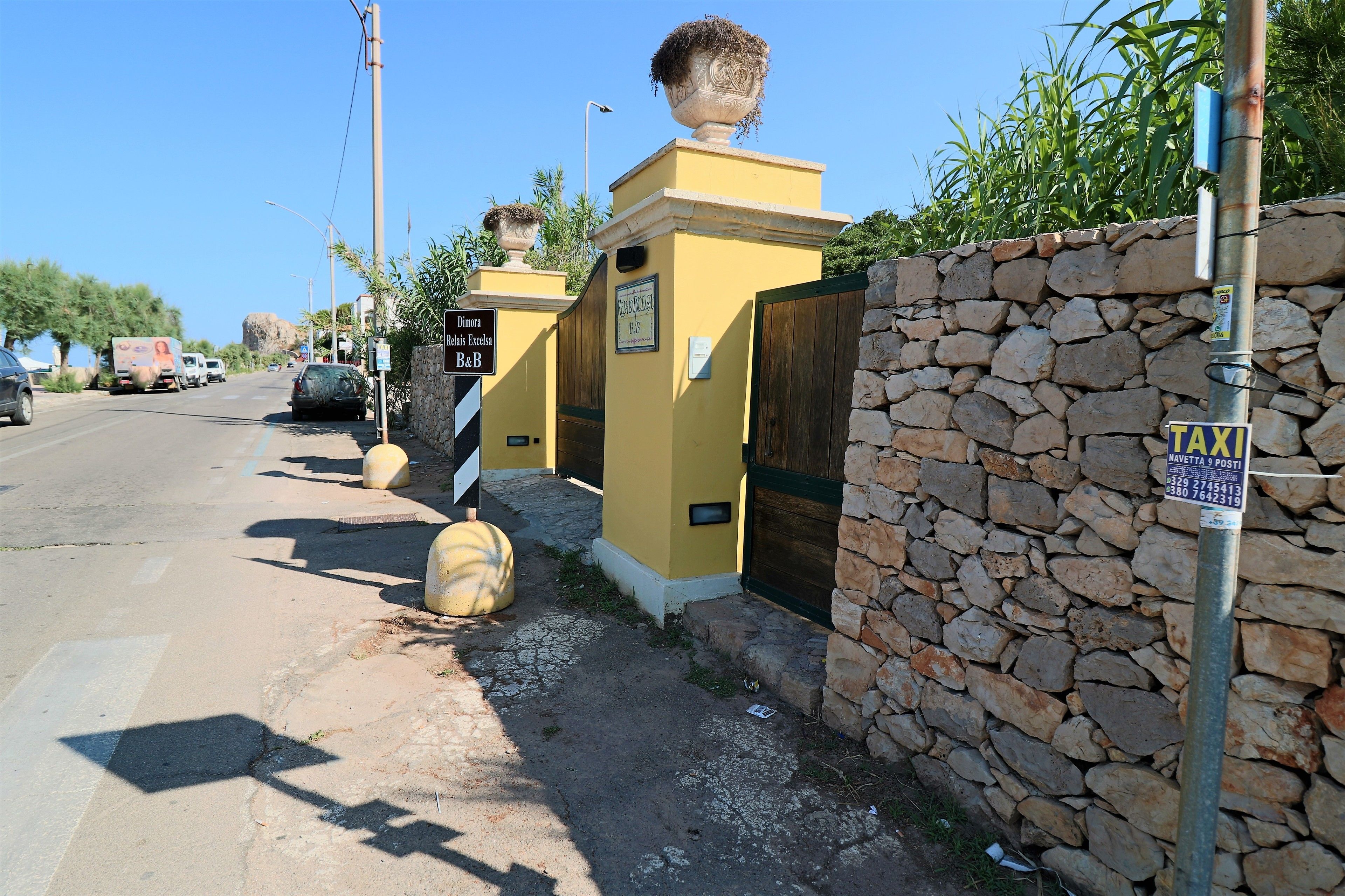 A yellow building with a stone wall and a taxi sign.