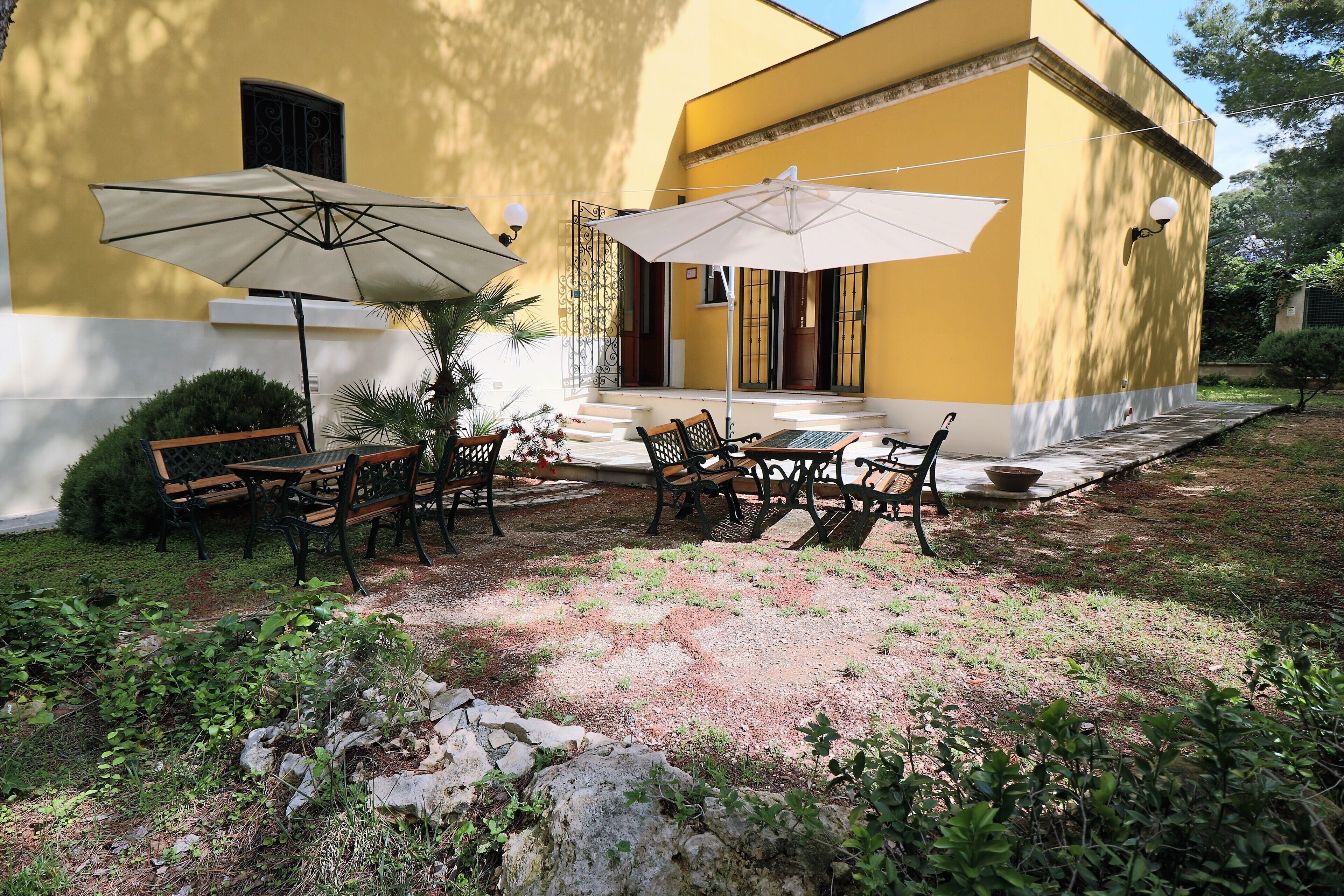 An outdoor seating area with tables and chairs, umbrellas, and a bench.