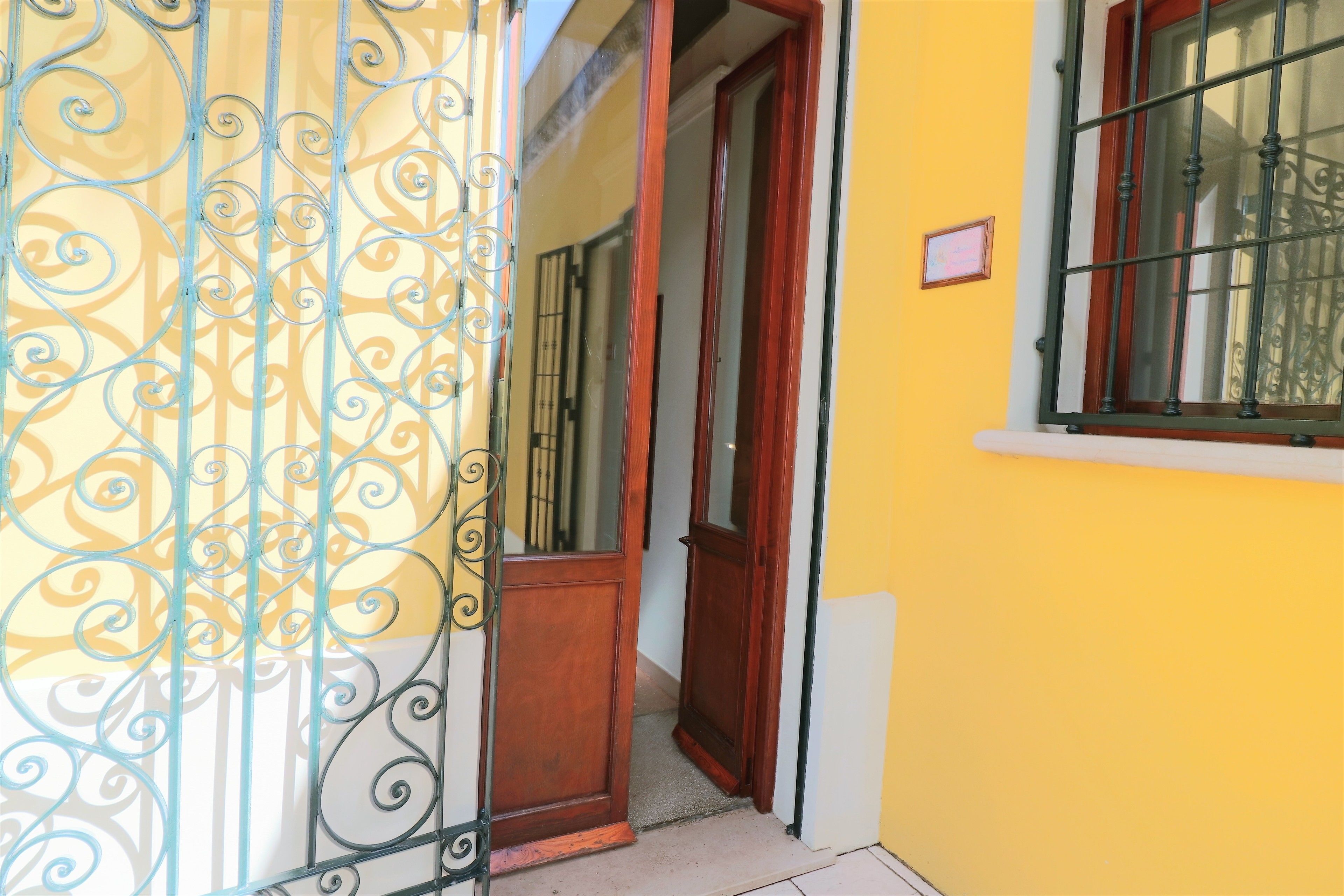A yellow building with a wooden door and a metal gate.