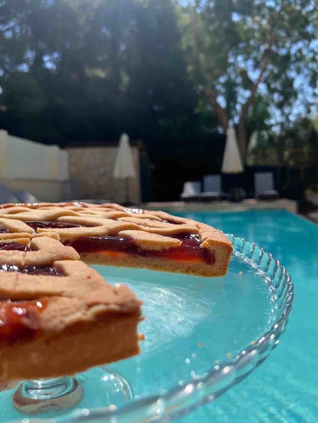 A pie on a glass serving dish by a poolside.