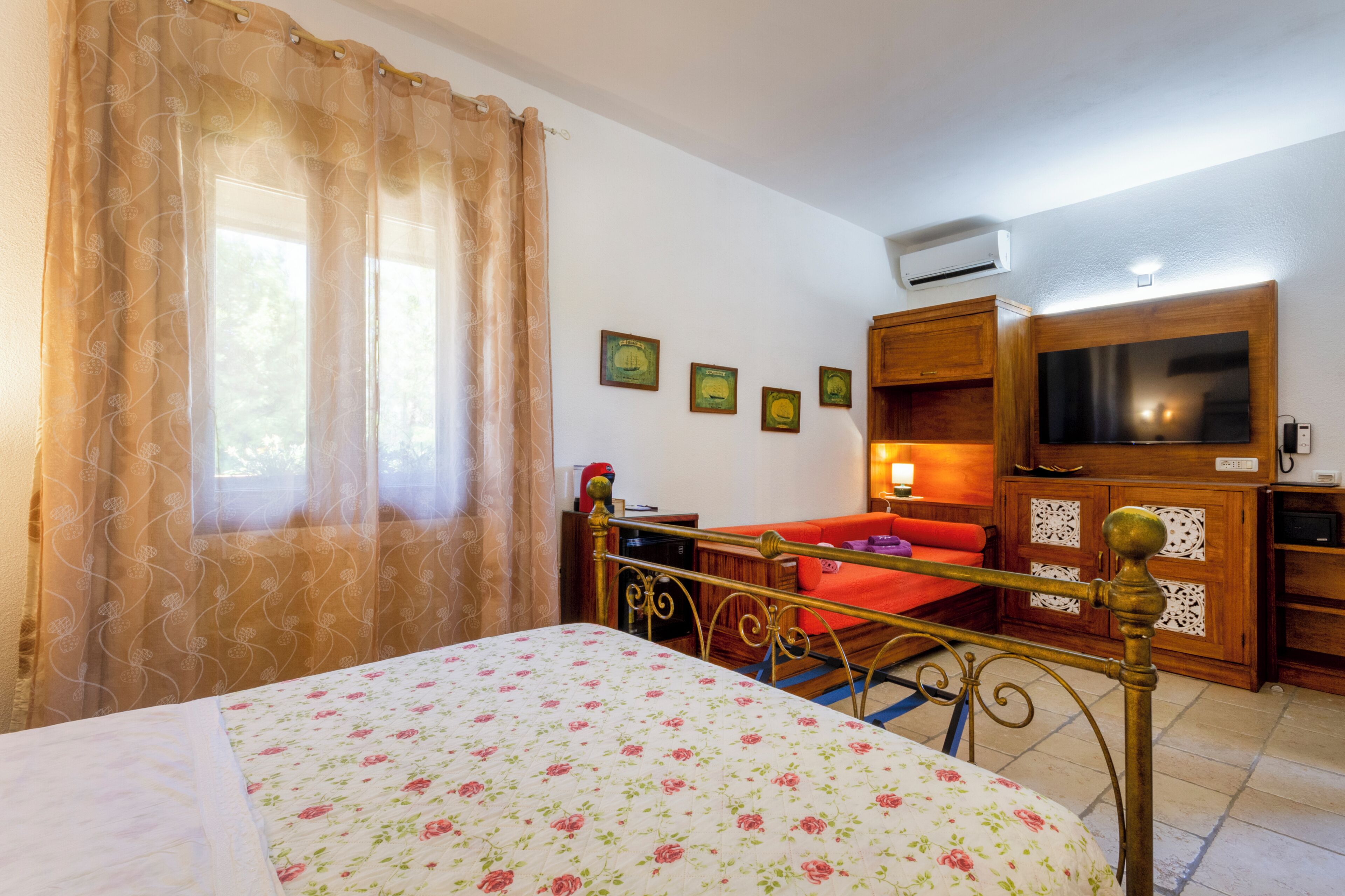 Una camera da letto con un letto, una televisione e un armadietto in legno.