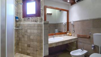 Een badkamer met een douche, wastafel, toilet en bidet.