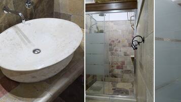 Un baño con un lavabo redondo, una ducha con puerta de vidrio y un portavasos en la pared.