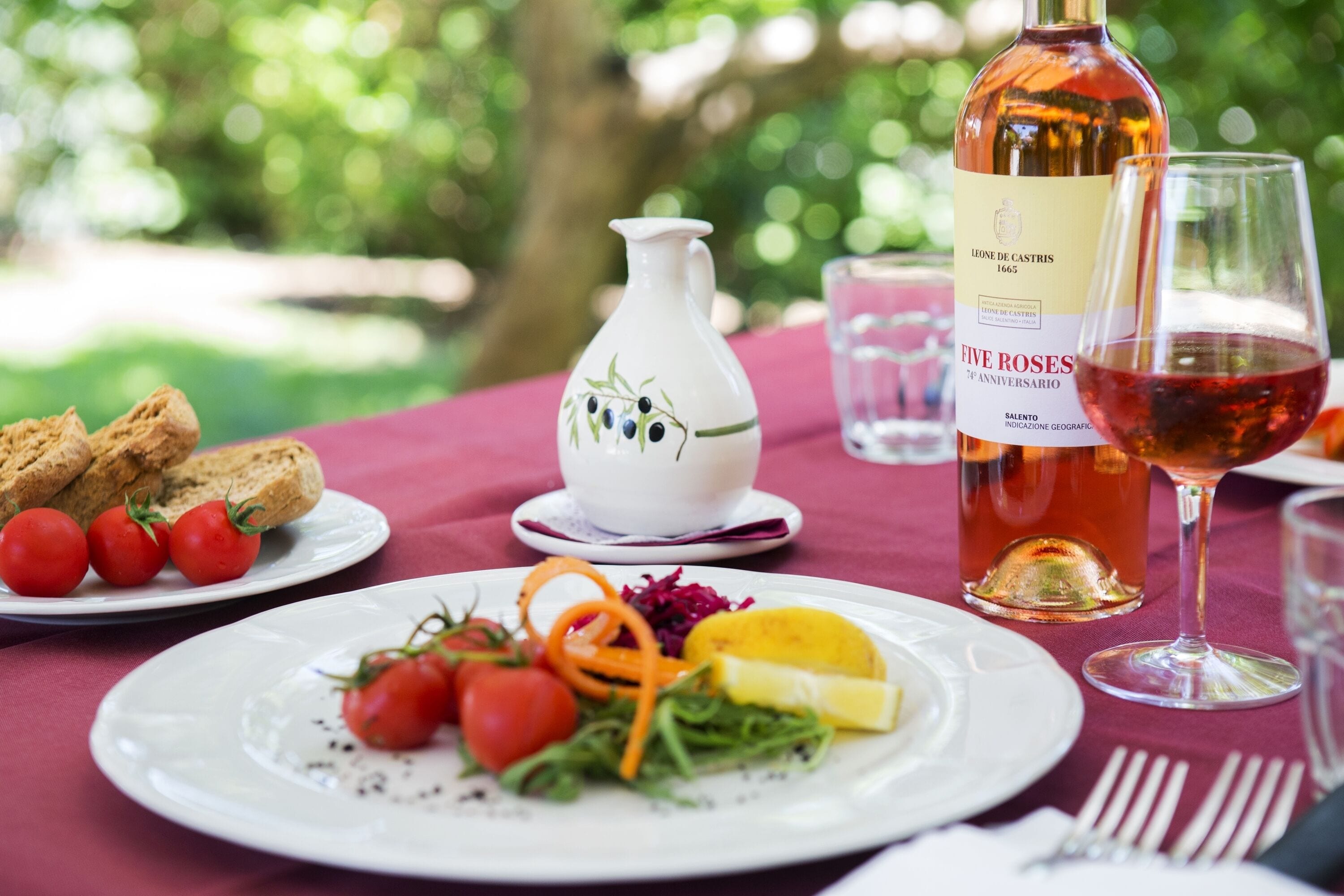 A table set with plates of food, a bottle of wine, and a pitcher.