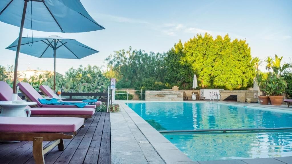 Un área de piscina con sillones de descanso y sombrillas.