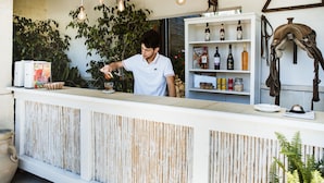 A bar area with a wooden counter, hanging light bulbs, and shelves with bottles. - Masseria L'Uliveto (Otranto)