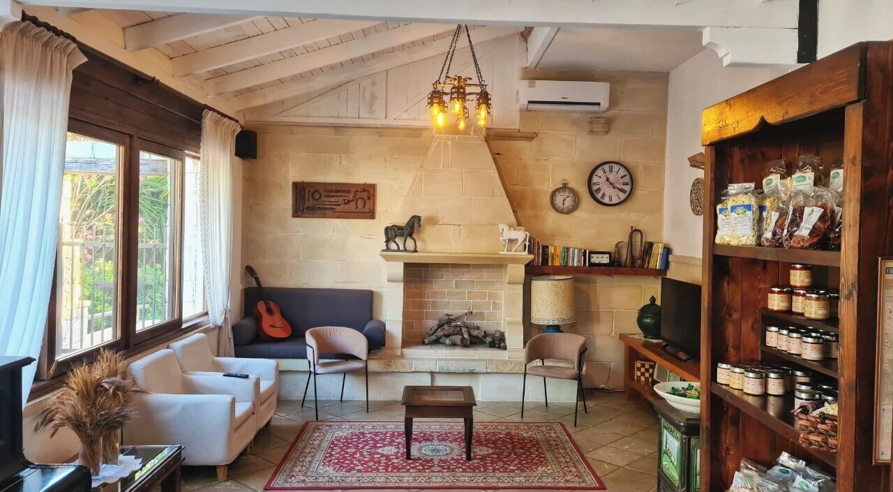 A cozy living room with a fireplace, a sofa, a coffee table, and a bookshelf filled with books and jars.